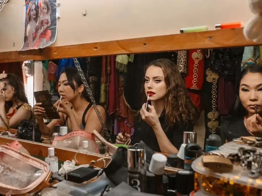 Niedziela Raluy junto a las contorsionistas del Circo Raluy Legacy maquillándose frente a un espejo antes de salir a escena.