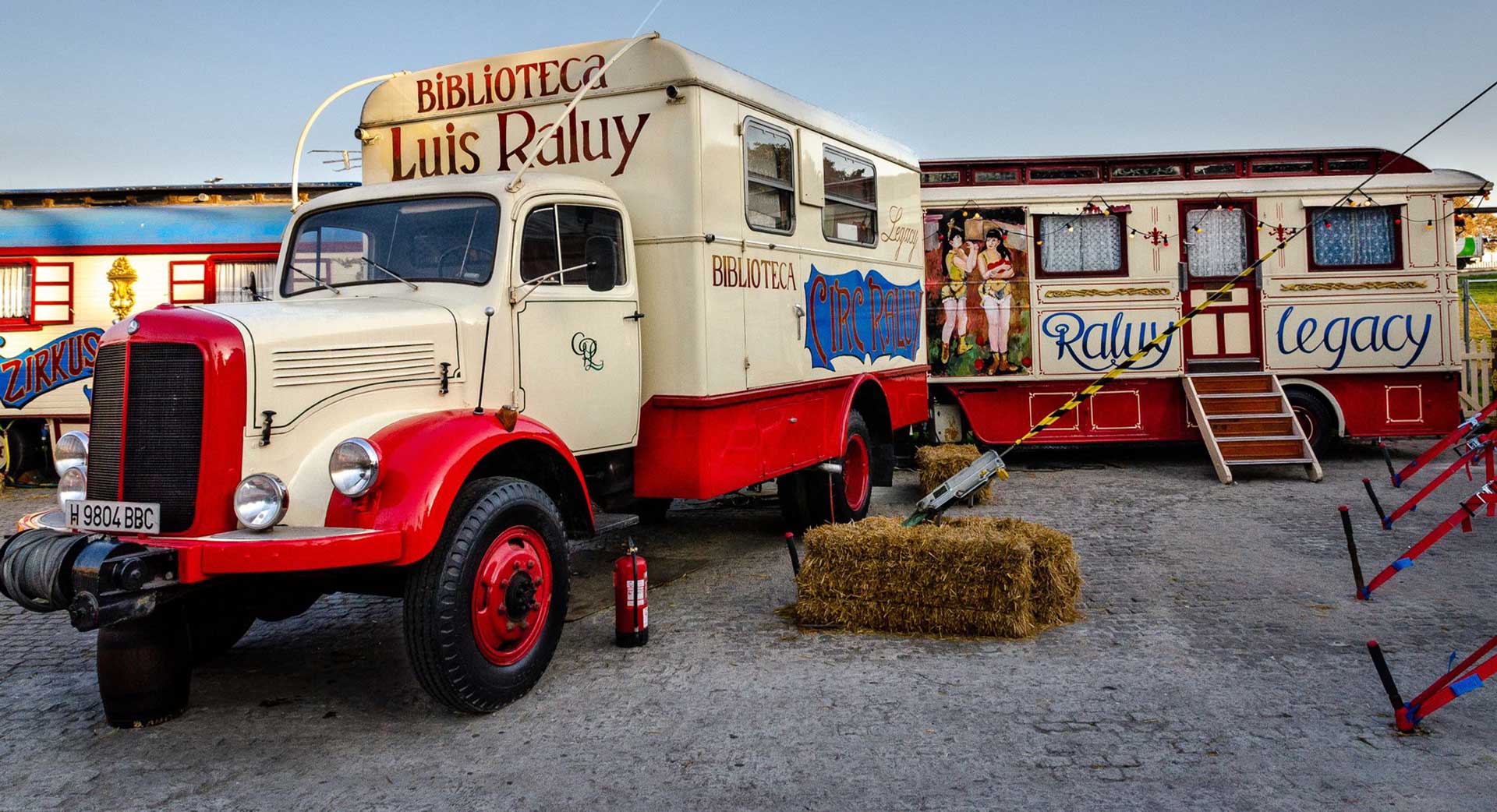 Camiones y caravana pintadas del circo Raluy Legacy. El camión blanco principal es la biblioteca de Luis Raluy