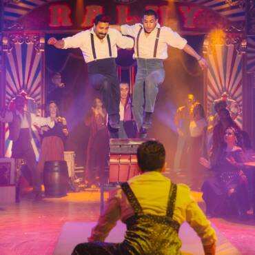 Acróbatas del Circo Raluy Legacy saltando sobre un trampolín. Detrás, artistas del circo aplaudiendo.