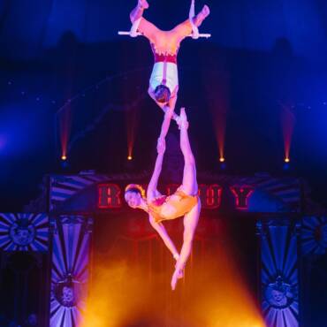 Benicio y Charmelle Raluy haciendo trapecio y una figura muy dificíl de hacer. Ella sonriendo al público y el de espaldas