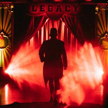 Pietro, artista del Circo Raluy Legacy, saliendo al escenario detrás de escena con humo y luces rojas.