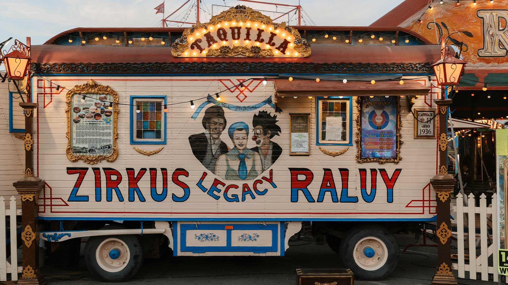 Taquilla de caravana del Circo Raluy Legacy con una mujer, un presentador y un payaso pintados.