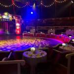 Interior de la carpa del Circo Raluy Legacy con luces de colores y mesas preparadas para un evento especial. Eventos.